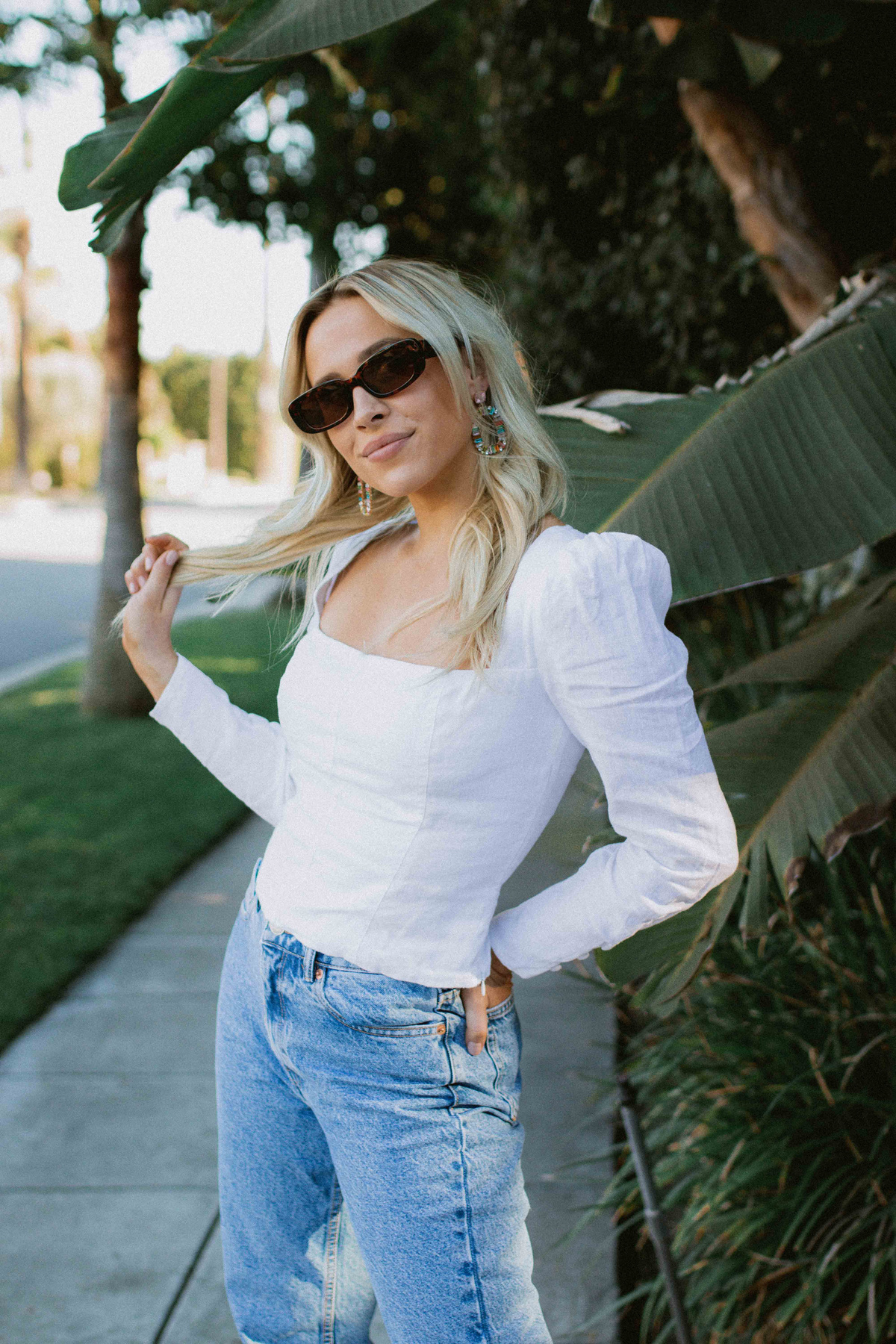Young Woman Posing near Tree Leaves for her Instagram Story